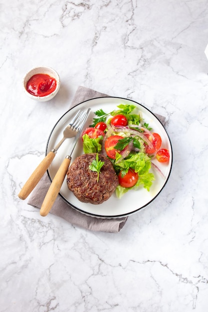 Hambúrguer de carne com salada de alface e tomate na vista superior de chapa branca