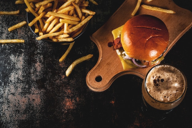 Hambúrguer de carne e queijo fresco com batatas fritas e copo de cerveja de gengibre escura