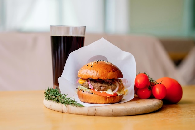 Hambúrguer de carne grelhada saboroso fresco com batata tomate queijo bacon alface e cola Fast food definido no terraço de verão Fotografado à luz do dia