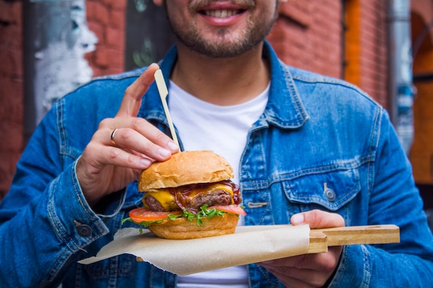 Foto hambúrguer de close-up nas mãos masculinas. um homem come um hambúrguer em um restaurante de fast food.