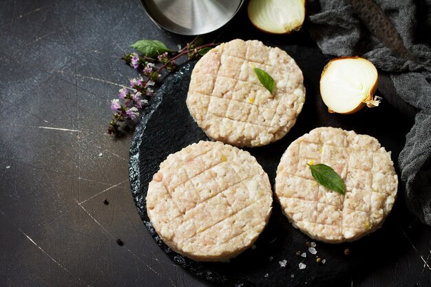 Hambúrguer de costeletas frescas de carne para hambúrgueres caseiros cozinhados com temperos no quadro negro