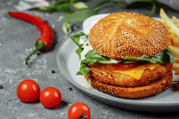 Hambúrguer de frango com batatas fritas e salada em uma velha mesa de concreto