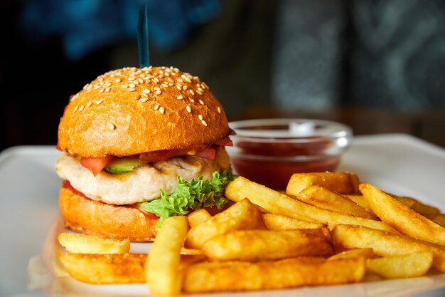 Hambúrguer de frango e batatas fritas em um prato branco