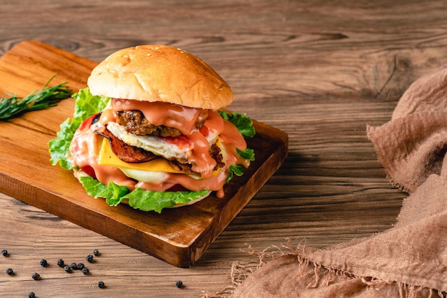 Hambúrguer de frango fresco e saboroso na mesa de madeira fotografia sombria