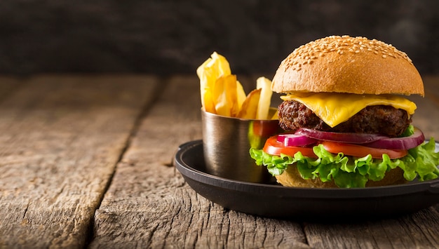 Hambúrguer de frente no prato e batatas fritas com espaço de cópia