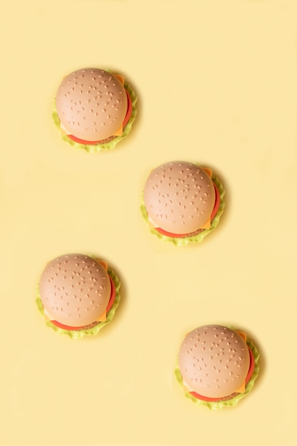 Hambúrguer de plástico, salada, tomate, sobre um fundo amarelo