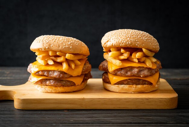 Foto hambúrguer de porco com queijo e batatas fritas.