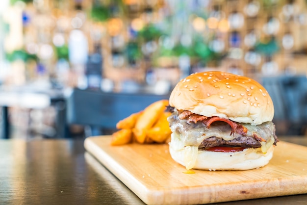 hambúrguer de queijo bacon com carne na placa de madeira no restaurante