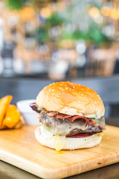 Foto hambúrguer de queijo bacon com carne na placa de madeira no restaurante