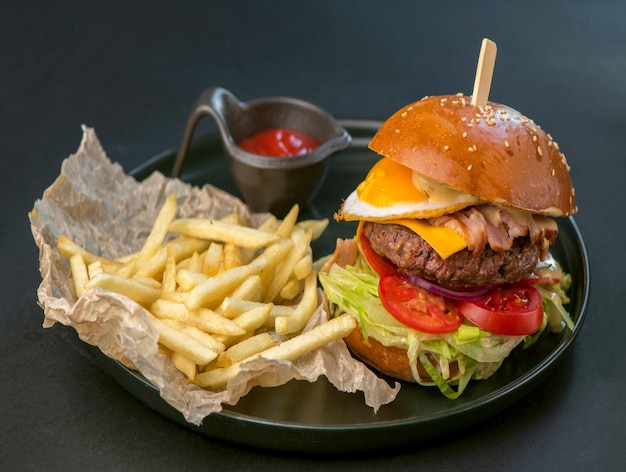 Hambúrguer delicioso, hambúrguer servido com batatas fritas em um fundo preto