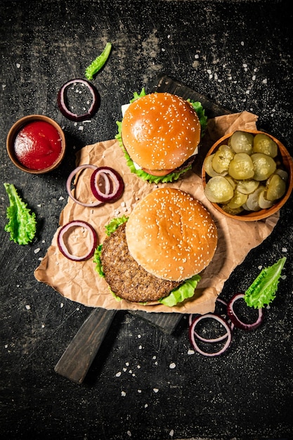 Hambúrguer em uma tábua com anéis de cebola molho de tomate e alface