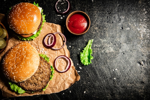 Hambúrguer em uma tábua com anéis de cebola molho de tomate e alface