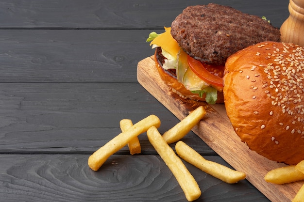 Hambúrguer fresco e batatas fritas em madeira preta