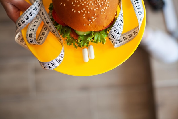 Foto hambúrguer gorduroso prejudicial com uma dieta de conceito de fita métrica
