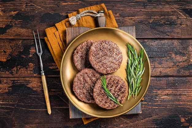 Hambúrguer grelhado de carne bovina com ervas e especiarias na chapa de aço Fundo de madeira Vista superior