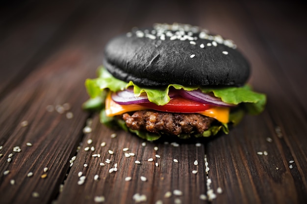 Foto hambúrguer preto caseiro com queijo. cheeseburger com pão preto o