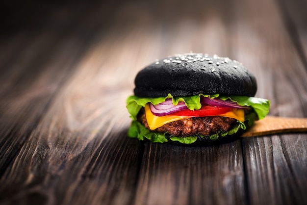 Hambúrguer preto caseiro com queijo. Cheeseburger com pão preto o