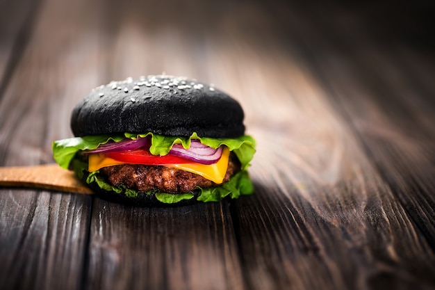 Hambúrguer preto caseiro com queijo. Cheeseburger com pão preto