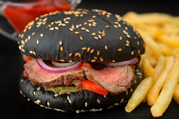 Hambúrguer preto com carne grelhada e legumes com fundo desfocado