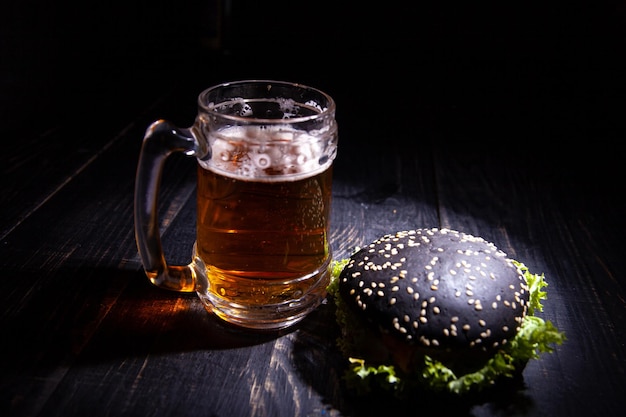 Hambúrguer preto e copo de cerveja isolado no preto. foco suave. foco seletivo.