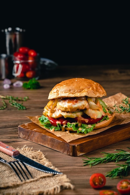 hambúrguer recheado com ovo frito pepino tomate maionese alface cebola em fundo de madeira