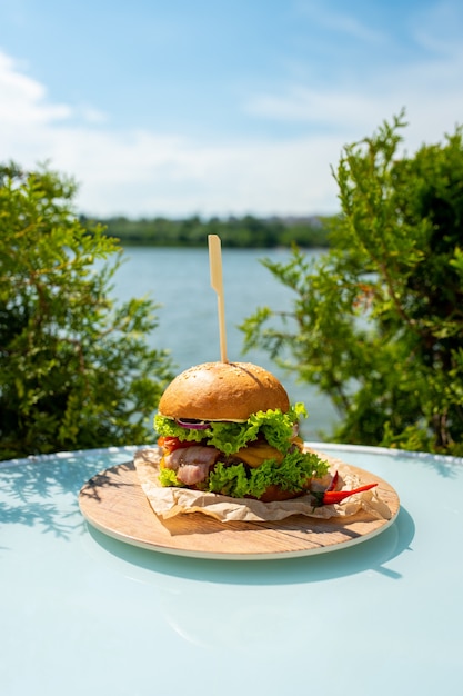 Foto hambúrguer suculento com bacon, alface, queijo, tomate, pimenta vermelha em resort de luxo