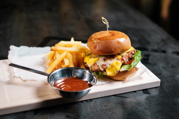 Hambúrguer suculento com batatas fritas e ketchup na placa de madeira