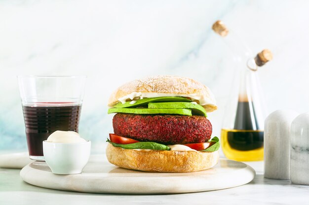 Hambúrguer vegano sem carne com abacate, tomate e espinafre na mesa e vinho tinto na taça