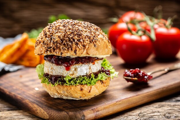 Hambúrguer vegetariano com molho de camembert e cranberry em uma placa de madeira rústica.