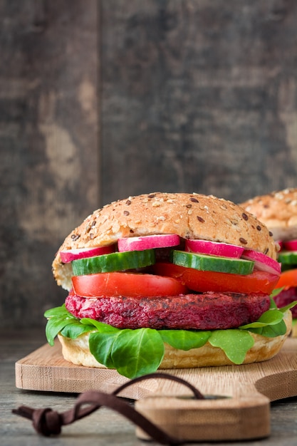 Hambúrguer vegetariano de beterraba com alface, tomate, rabanete e pepino de cordeiro na mesa de madeira rústica