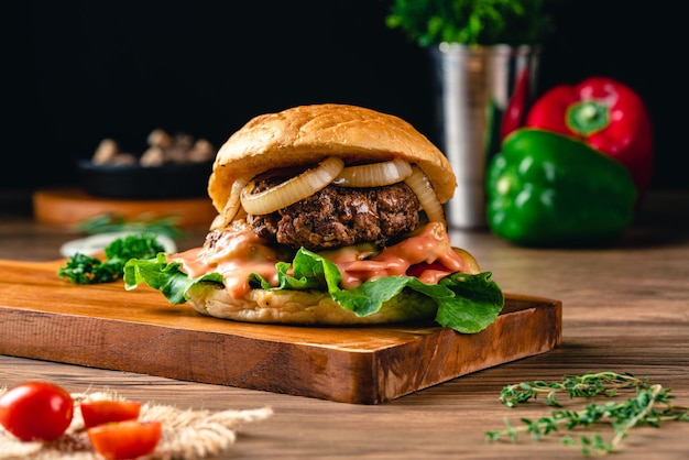 Hambúrgueres caseiros grelhados frescos com carne, tomate, ovo frito, queijo e alface em fundo de madeira