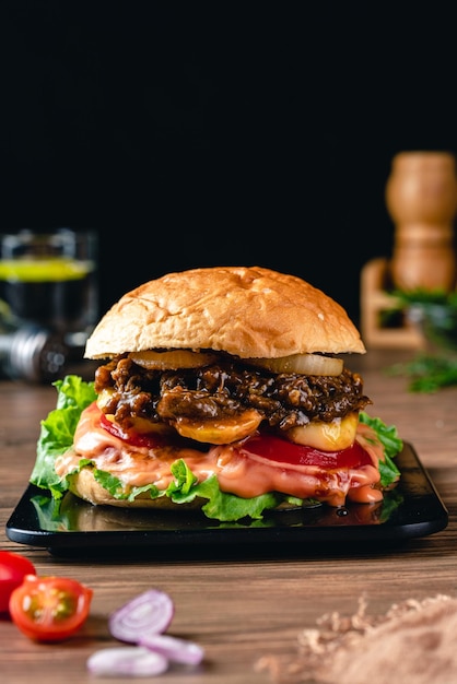 Hambúrgueres caseiros grelhados frescos com carne, tomate, ovo frito, queijo e alface em fundo de madeira