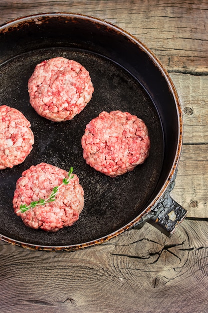 Hambúrgueres crus de carne orgânica em uma frigideira