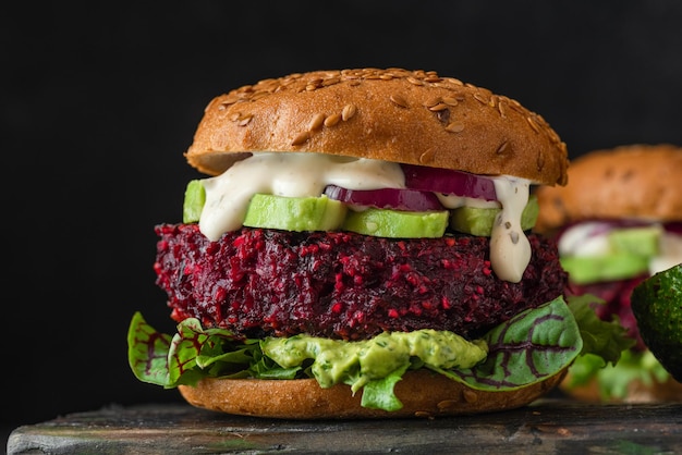 Hambúrgueres de beterraba vegetariana com maionese de cebola abacate e salada mista em fundo preto Conceito de fast food vegan saudável