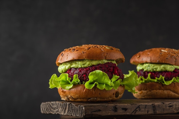 Hambúrgueres de beterraba vegetariana com molho de abacate e salada de alface em fundo preto Fast food vegan saudável