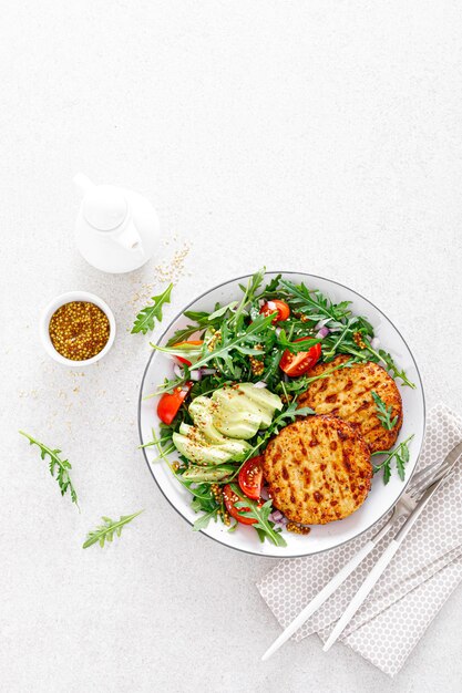 Foto hambúrgueres de frango grelhado abacate e salada de legumes frescos com vista superior de tomate e rúcula