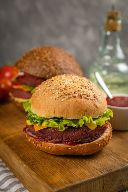 Hambúrgueres frescos com carne e vegetais veganos, polvilhados com sementes de gergelim