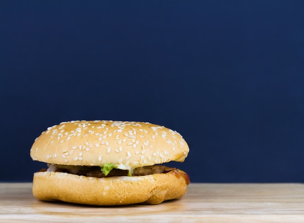 Hamburguesa en bandeja de madera con fondo gris