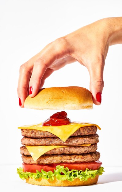 Foto hamburguesa de bistec cuádruple con queso cheddar y lechuga en una mano