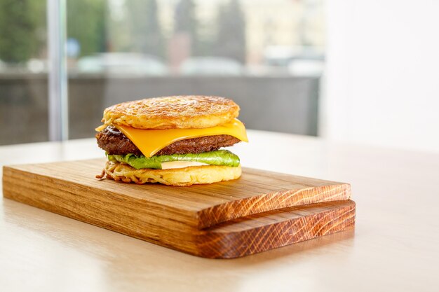 Hamburguesa con carne y ensalada en un escritorio de madera.