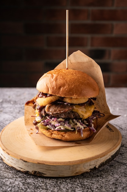 Hamburguesa de carne jugosa con verduras frescas y especias. bollo suave fragante y salsas naturales. vista lateral. sobre un fondo oscuro, para menús y anuncios