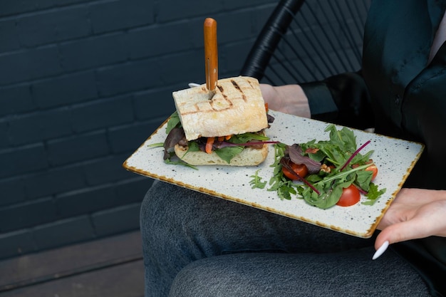 Hamburguesa con carne en una terraza de verano en manos femeninas