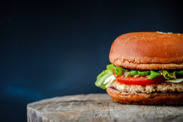 Hamburguesa casera apetitosa en una mesa de madera sobre fondo azul oscuro