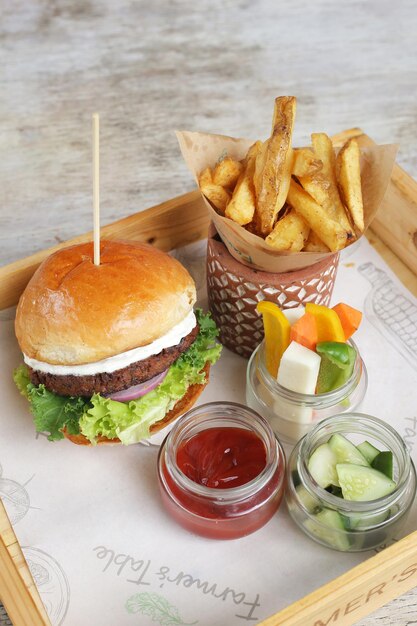 Hamburguesa casera a base de plantas a la parrilla con gajos de ensalada y salsa de tomate servida en una vista lateral de la tabla de servir