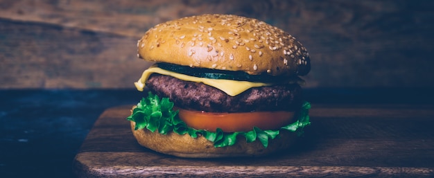 Hamburguesa casera (hamburguesa con queso) con carne sobre un fondo de madera. Hamburguesa casera clásica.