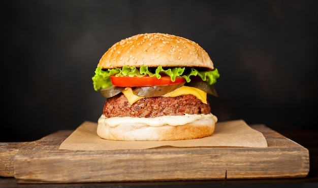 Hamburguesa casera con lechuga, tomate, queso y pepino en una tabla para cortar