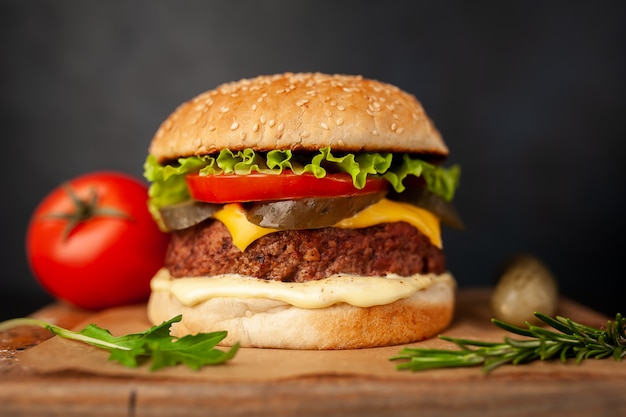 Hamburguesa casera con lechuga, tomate, queso y pepino en una tabla para cortar