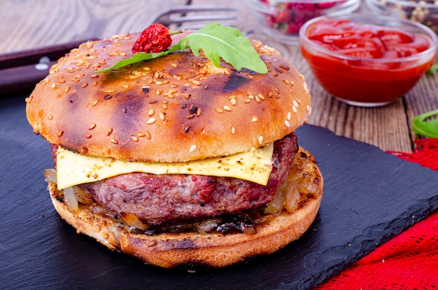 Hamburguesa casera con pan de sésamo y carne molida sobre piedra negra.