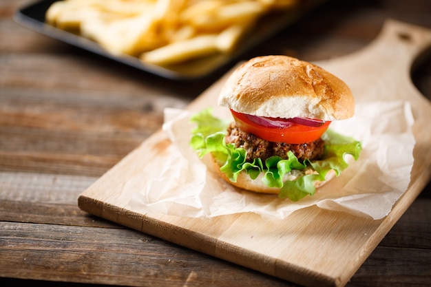 Hamburguesa casera con papas fritas en mesa de madera