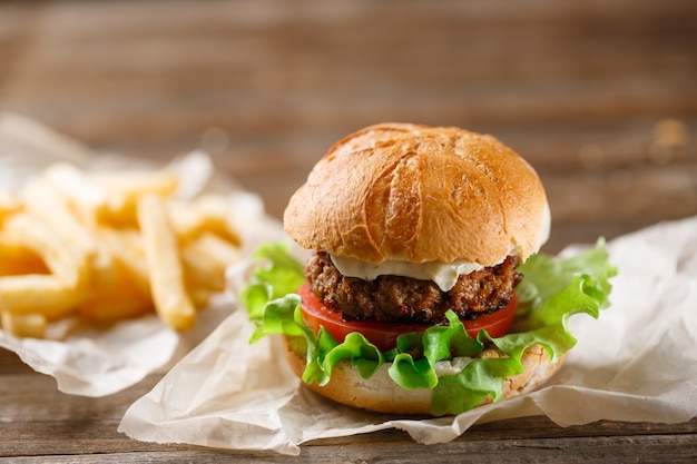 Hamburguesa casera y papas fritas en una placa de madera